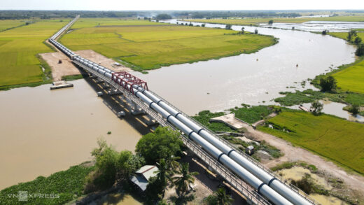 Steel pipes carry water across the Vam Co Dong River